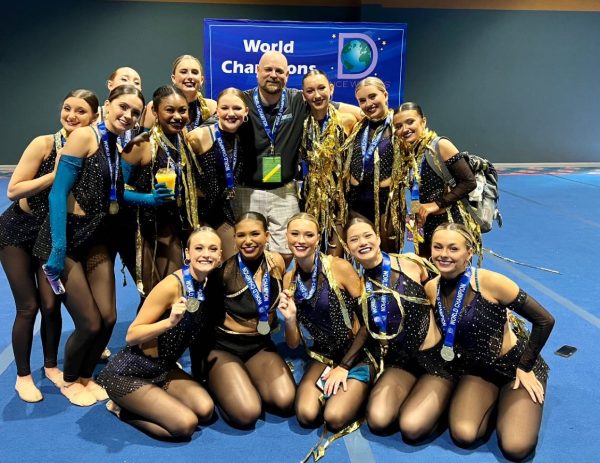  Picture of athlete Delaney Mulligan and trainer Kevin Brown alongside the Kentucky based dance team after winning a 2023 world championship title.
